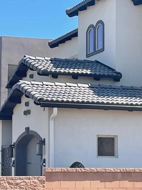 A house featuring a distinctive roof adorned with black and white tiles, showcasing a striking architectural design.
